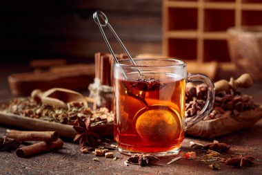 Tarçınlı, anasonlu ve kurutulmuş otlu Noel çayı. Kahverengi bir masada baharatlı bitki çayı..