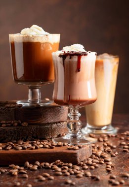 Kahverengi arka planda krem şantili ve çikolata soslu sıcak kahve ve çikolata içecekler..