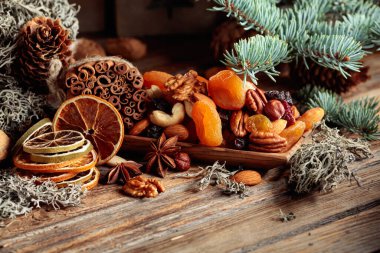 Eski ahşap bir masada kurumuş meyve ve fındık. Kurutulmuş turunçgiller, kayısılar, kuru üzümler, çeşitli fındıklar, tarçın çubukları ve anason içeren bir Noel..