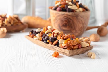 Beyaz ahşap bir masada fındık ve kuru üzüm karışımı. Sunulan kuru üzüm, ceviz, fındık, ceviz, ceviz, ceviz ve badem..