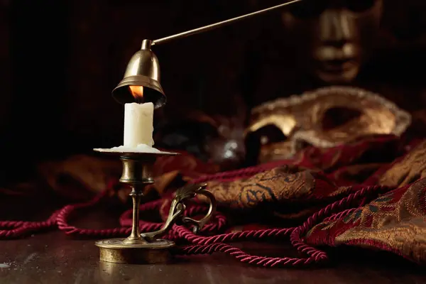 在旧的黄铜烛台上燃着蜡烛 在旧的木制桌子上挂着狂欢节的面具 — 图库照片