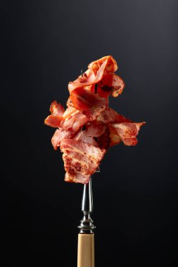 Siyah arka planda kızarmış pastırma dilimleri. Kızarmış domuz pastırması..