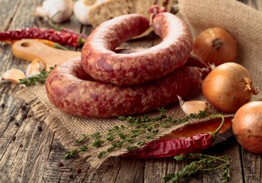 Kurutulmuş sosis, kekik, soğan, sarımsak ve biber. Eski ahşap bir masada sosis ve baharat..
