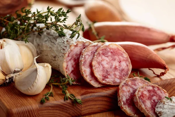 Traditional dry-cured sausage with thyme, garlic, and onion. Dry-cured sausage on a wooden table.
