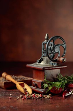 Eskimiş biber değirmeni aşçılık aletleri, baharatlar ve biberiye ile kahverengi arka planda. Boşluğu kopyala.