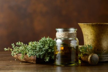 Eski ahşap bir masada taze kekik ile bir şişe kekik yağı. Boşluğu kopyala.