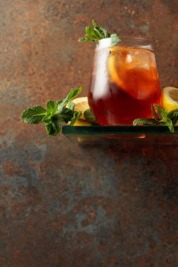 Donmuş bardakta limonlu buzlu çay ve nane şekeri. Köy duvarının arka planında ferahlatıcı bir içecek. Boşluğu kopyala. 