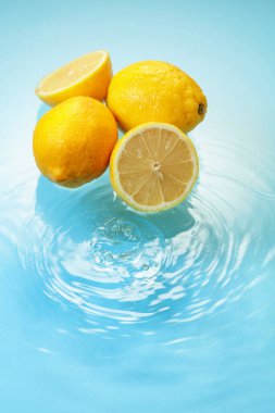 Ripe juicy lemons on a blue background with water splashes. Copy space.