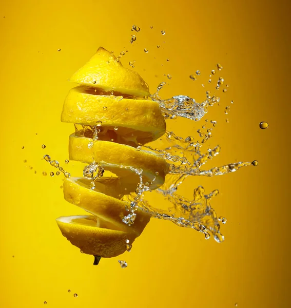 Fresh lemon and splashes of water on a yellow background.
