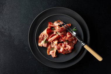  Siyah tabakta biberiyeli kızarmış pastırma dilimleri. Uzayı kopyala Üst görünüm.