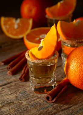 Tarçınlı portakal likörü ve eski ahşap bir masada taze meyveler..