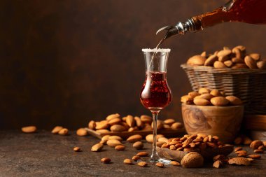 Alkolik İtalyan likörü Amaretto. Şarap masasında badem fıstığı var. Boşluğu kopyala.