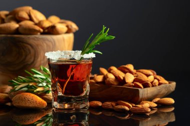 Güçlü alkolik İtalyan likörü Amaretto. Siyah arka planda badem fıstığı var..