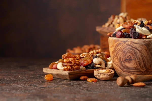Mix of nuts and raisins on a brown rustic background. Presented raisins, walnuts, hazelnuts, cashews, pecans, and almonds.