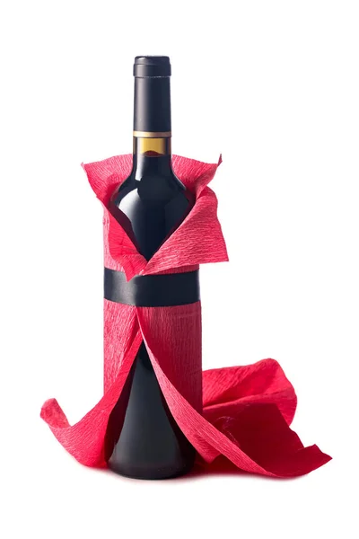 Bottle of red wine wrapped in crepe paper isolated on a white background. The bottle looks like a woman in a red evening dress.