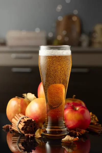 Apple cider in high glass. Fresh drink with apples, cinnamon, and anise on a black background.