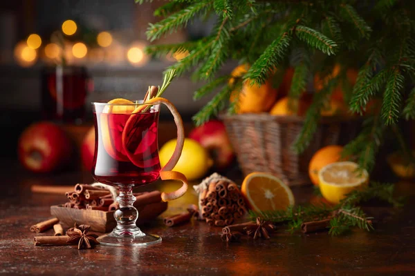 Hot mulled wine with citrus, apples, cinnamon, anise, and rosemary. Christmas mulled red wine with spices and fruits on a brown rustic table. Traditional hot drink at Christmas time.