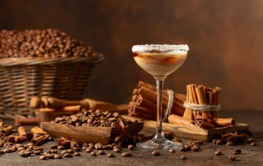 Kahverengi arka planda İrlanda kreması ve kahve likörü. Kahve çekirdekleri, tarçın çubukları ve anason masaya saçılmış..