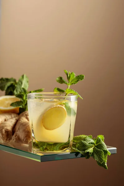 Ginger ale beer cocktail with lemon and mint in a frozen glass. Refreshing summer cocktail with natural ice, ginger, lemon, and mint. Copy space.