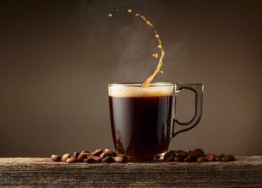 Kahverengi arkaplanlı espresso bardağı. Kahve fincanı ve kavrulmuş kahve çekirdekleri eski bir tahtanın üzerinde..