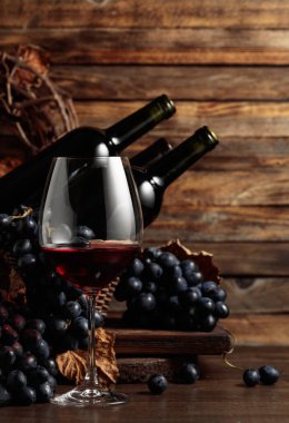 Red wine and blue grapes. Wine and grapes in a vintage setting on an old wooden table.