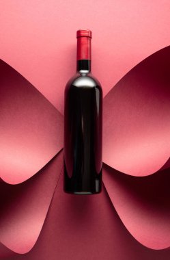 Kırmızı arka planda bir şişe kırmızı şarap. Üst görünüm.