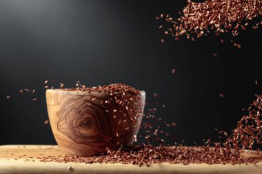 Grains of flaxseed are poured into the wooden bowl. Copy space.
