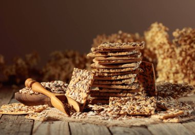 Eski ahşap bir masada ayçiçeği ve keten tohumlu çıtır krakerler. Basit sağlıklı yiyecekler..