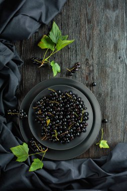 Black currant with leaves on a old wooden table. Top view.