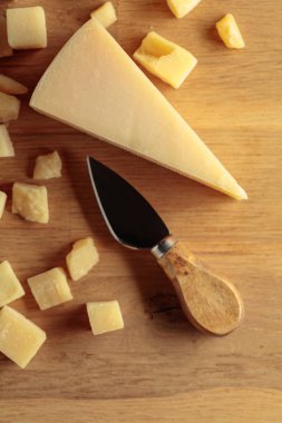 Parmesan cheese with knife on a wooden background. Copy space.