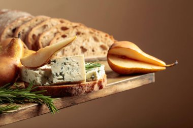 Mavi peynirli, armutlu ve biberiyeli sandviç. Eski ahşap bir masada ciabatta, mavi peynir, armut ve biberiye.