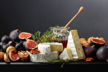 İncirli, üzümlü, cevizli, ballı ve kekikli Camembert peyniri. Siyah arka planda meyveli yumuşak peynir..