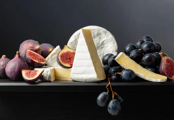 芝士加无花果和葡萄带有黑色背景水果的软奶酪 — 图库照片