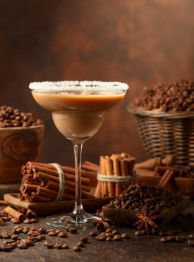 Çikolatalı martini kokteyli ya da kahverengi arka planda İrlanda kremalı likör. Kahve çekirdekleri, tarçın çubukları ve anason masaya saçılmış..