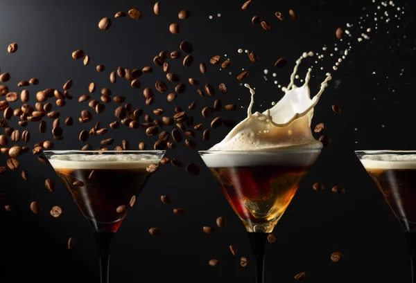 Espresso Martini drink with splashes and falling coffee beans on a black background. Copy space.