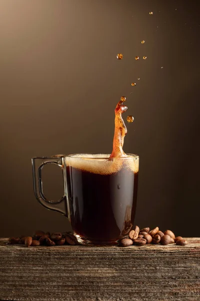 Espressokaffeebecher Mit Spritzern Auf Braunem Hintergrund Kaffeetasse Und Geröstete Kaffeebohnen — Stockfoto