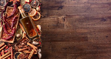 Eski ahşap bir masada bir şişe zeytinyağı ve çeşitli baharatlar. Üst görünüm.