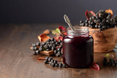 Yaban mersini reçeli ve taze böğürtlen eski ahşap bir masanın üzerinde yapraklarla.