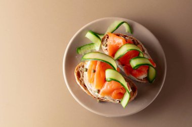 Tütsülenmiş alabalık, krem peynir, salatalık ve bej kapari. Üst görünüm, alanı kopyala.