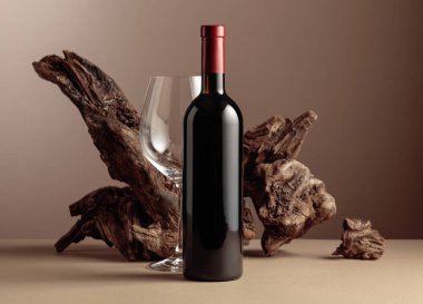 Bej arka planda yıpranmış eski bir pürüz olan bir şişe ve bir bardak kırmızı şarap. Kopyalama alanı ile ön görünüm.