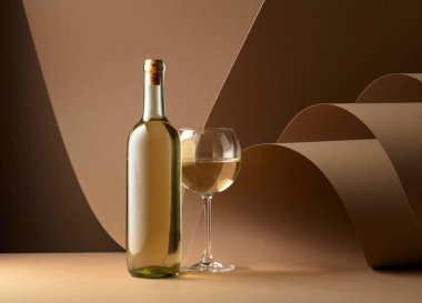 Bottle and glass of white wine on a beige background. Copy space.