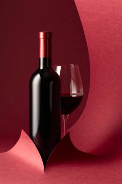 Kırmızı arka planda bir şişe kırmızı şarap. Boşluğu kopyala.