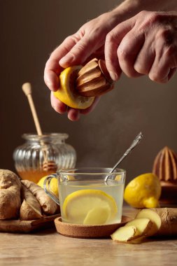 Kahverengi seramik masada limonlu ve ballı zencefil çayı. Meyve suyu eski bir meyve sıkacağıyla limondan sıkılır..
