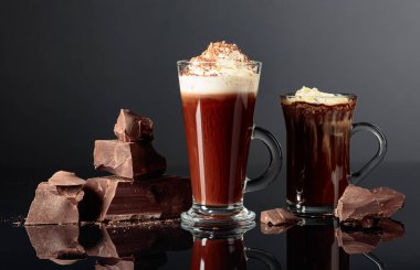 Krem şanti ve koyu bir arka plan üzerinde koyu çikolata parçaları ile sıcak çikolata. Kopyalama alanı.