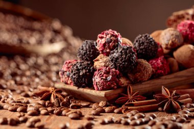 Tahta bir masada çeşitli çikolata şekerlemeleri. Tarçın, anason ve kahve çekirdekli lezzetli çikolatalı trüf..