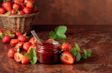 Çilek reçeli ve taze böğürtlen ve eski kahverengi bir masanın üzerinde yapraklar. Boşluğu kopyala.