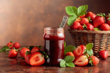 Çilek reçeli ve taze böğürtlen ve eski kahverengi bir masanın üzerinde yapraklar. Boşluğu kopyala.