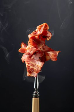 Siyah arka planda kızarmış pastırma dilimleri. Kızarmış domuz pastırması..