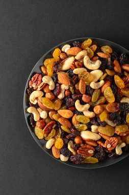 Siyah arka planda kurutulmuş fındık ve kuru üzüm karışımı. Üst Manzara. Boşluğu kopyala.