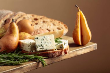 Mavi peynirli, armutlu ve biberiyeli sandviç. Eski ahşap bir masada ciabatta, mavi peynir, armut ve biberiye.